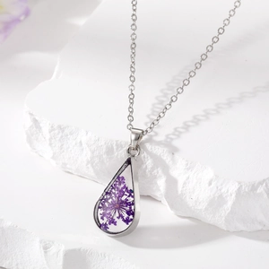 Detailed view of silver teardrop necklace with real dried purple flower in resin