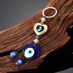 Porte-clés œil grec avec pendentif en verre bleu et cœur doré sur fond bois vintage