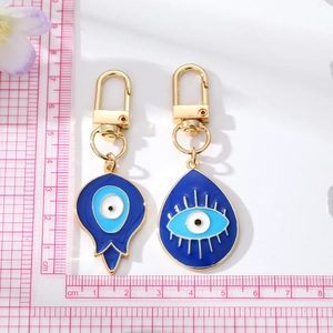 Close-up of vintage teardrop evil eye keychains showing sizes with a pink cm ruler