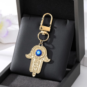 Nahaufnahme von goldenem Hamsa-Hand Schlüsselanhänger mit blauem Auge und Karabiner