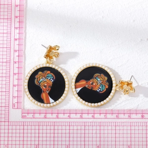 Pendientes étnicos redondos dorados con retrato de mujer africana, perlas y regla