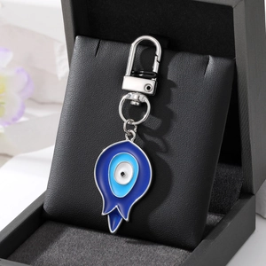 Detailed view of Turkish Evil Eye keychain with blue resin teardrop pendant on black box