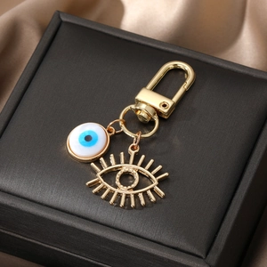 Porte-clés œil bleu doré avec breloque de cils sur une boîte cadeau de luxe noire