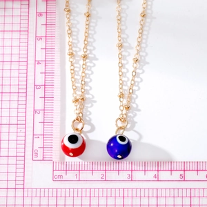 Macro view of blue and red Evil Eye ball pendants on gold-plated satellite chains