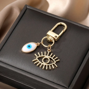 Porte-clés œil bleu doré avec émail blanc et pendentif cils ajouré sur fond de soie
