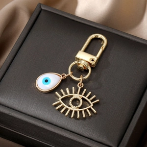 Porte-clés œil maléfique doré avec pendentif goutte blanche et breloque cils ajourée