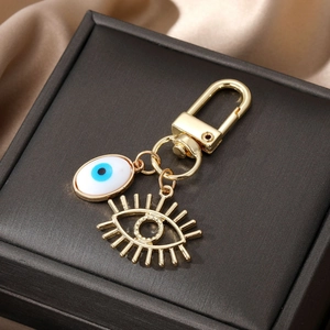 Vue détaillée du porte-clés œil bleu doré avec pendentif cils creux sur boîte noire