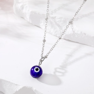 Detail of blue evil eye pendant with heart center on a silver chain necklace