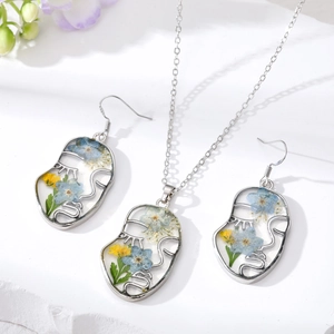 Parure de bijoux visage abstrait avec fleurs séchées dans une monture en résine argentée