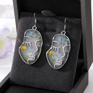 Boucles d'oreilles silhouette visage avec fleurs séchées naturelles et résine transparente