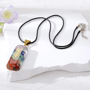 Dettaglio del ciondolo chakra in resina con pietre naturali su una superficie di pietra