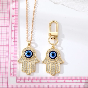 Macro-opname van gouden Hamsa Hand hanger met blauw oog en kristallen details, 4,2 cm groot