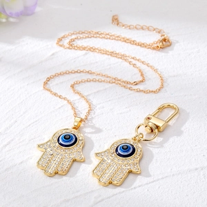 Detailopname van gouden Hamsa-hand met blauw boze oog en fonkelende kristallen op wit