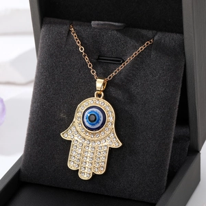 Gouden Hamsa Hand ketting met kristallen en blauw boze oog in een zwarte sieradendoos