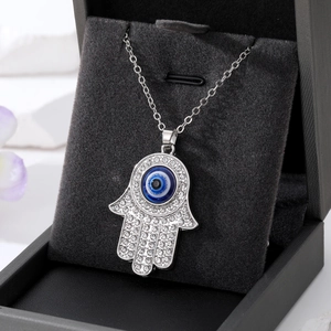 Hamsa Hand ketting met blauw Evil Eye en witte zirkoon op een donkere sieradendoos
