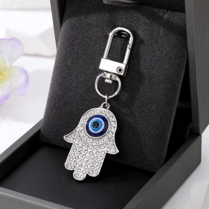 Macro-opname van zilveren Hamsa Hand sleutelhanger met kristallen en blauw oog