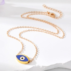 Collier élégant en chaîne dorée avec pendentif œil maléfique bleu sur fond de pierre blanche