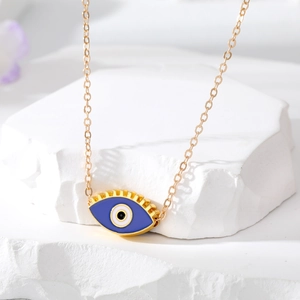 Détail macro du pendentif œil maléfique doré avec émail bleu et longs cils dorés