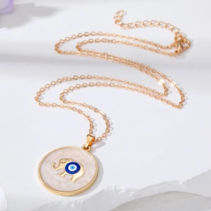 Golden elephant evil eye necklace with sand dripping pendant on a white stone background