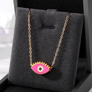 Collier pendentif œil maléfique en émail rose avec chaîne dorée sur boîte à bijoux