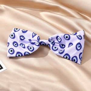 Vue détaillée d'une barrette à nœud en soie avec motif œil bleu sur satin