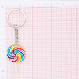 Colorful rainbow lollipop keychain with silver metal ring on pink grid background