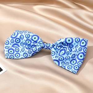 Détail du motif Evil Eye bleu et blanc sur un nœud de cheveux en soie avec fond en satin doux