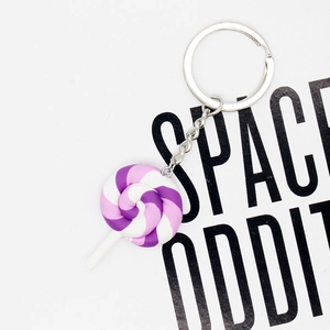 Purple and white spiral rainbow lollipop keychain with silver metal ring on white background
