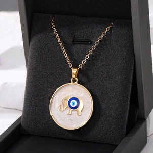 Detail of gold elephant pendant with evil eye motif on a black velvet jewelry box