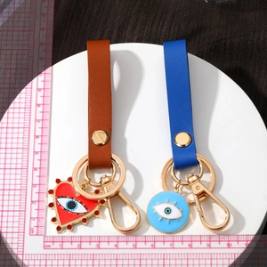 Detail of geometric evil eye leather keychains with heart and pearl pendant accents