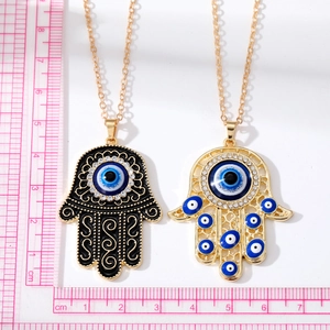 Détail macro de pendentifs main de Fatma avec œil bleu maléfique et motifs évidés dorés