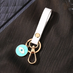 Detail of evil eye keychain with white leather strap and gold-tone hardware