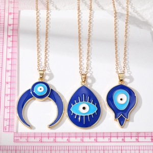 Detailed view of three gold alloy evil eye pendants with dimensions on a ruler
