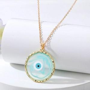 Elegant gold evil eye necklace with blue resin pendant displayed on white pedestals