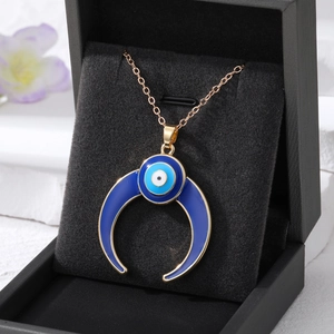 Close-up of golden crescent moon evil eye necklace pendant on black velvet box