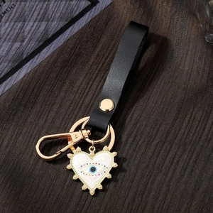 Detail of heart evil eye keychain with white pearls on a black leather strap