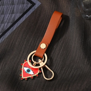 Detail of red heart pendant with evil eye motif and leather strap on gold keychain