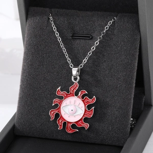 Macro shot of silver sunburst necklace with pink evil eye enamel pendant on black velvet
