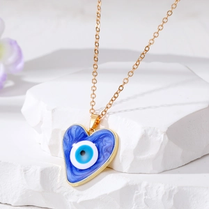 Golden heart-shaped evil eye pendant necklace with blue enamel on a white stone base
