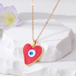 Macro shot of heart-shaped blue evil eye pendant on a gold chain over white stone