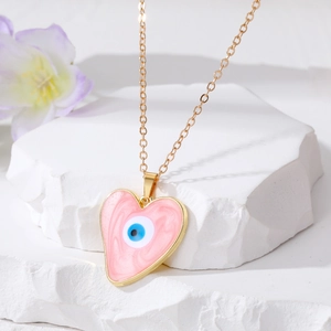 Detail of heart evil eye pendant with pink resin texture on white stone block
