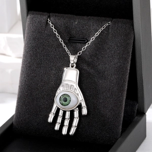 Collier bohème avec pendentif main argenté et œil maléfique vert dans un écrin à bijoux