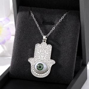 Détail du pendentif Main de Fatma argenté avec œil bleu sur coussin à bijoux noir