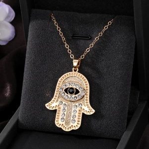 Macro view of gold Hamsa hand pendant with sparkling rhinestones and evil eye detail