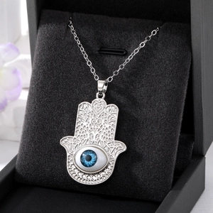 Vue détaillée du pendentif Main de Fatma avec œil bleu sur fond de velours noir