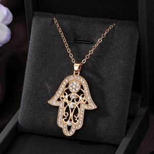 Close-up of a golden Hamsa Hand pendant with rhinestones on a black velvet box