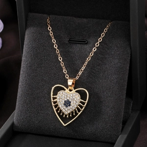 Macro shot of a gold heart pendant with sparkling white rhinestones and a blue flower detail