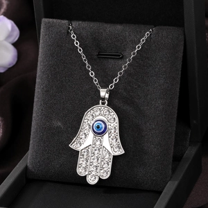 Detailed macro view of Hamsa Hand pendant with rhinestones and blue Evil Eye on velvet