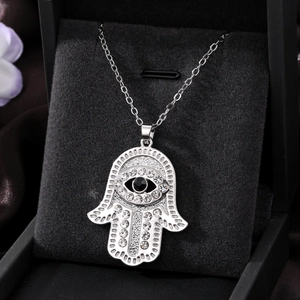 Detailed close-up of Hamsa Hand pendant with rhinestones and black eye on velvet