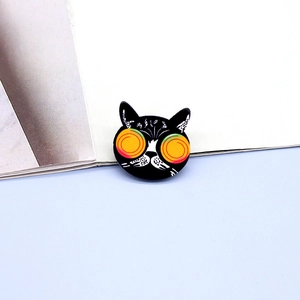 Cartoon black cat acrylic brooch with hypnotic orange spiral eyes on blue background